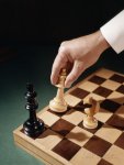 h-armstrong-roberts-hand-moving-chess-piece-to-checkmate.jpg
