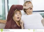 shocked-woman-covering-man-s-eyes-watching-tv-home-women-35921129.jpg