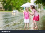stock-photo-two-cute-little-sisters-standing-in-a-puddle-holding-umbrella-on-a-rainy-summer-da...jpg