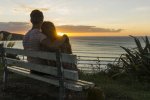 couple-in-love-sitting-on-bench-looking-at-sunset-UUF007965.jpg