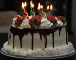 White+cream+birthday+cake+with+chocolate+sauce+and+strawberries+topping+and+cool+curved+candles.JPG